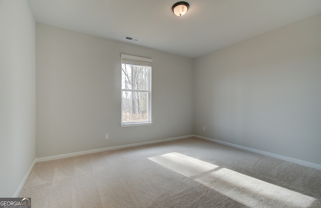 unfurnished room featuring light colored carpet, visible vents, and baseboards