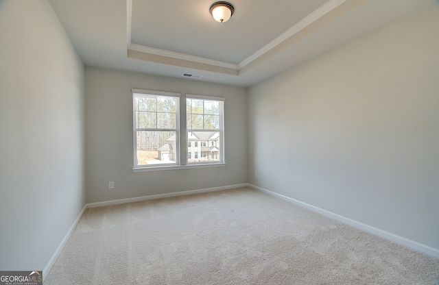 carpeted empty room with a tray ceiling, baseboards, visible vents, and ornamental molding