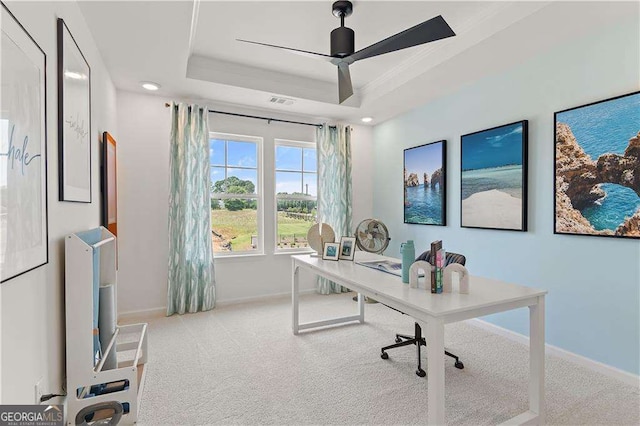 carpeted office featuring a raised ceiling and ceiling fan