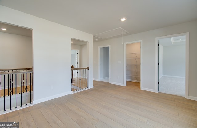 empty room featuring baseboards, recessed lighting, attic access, and light wood-style floors