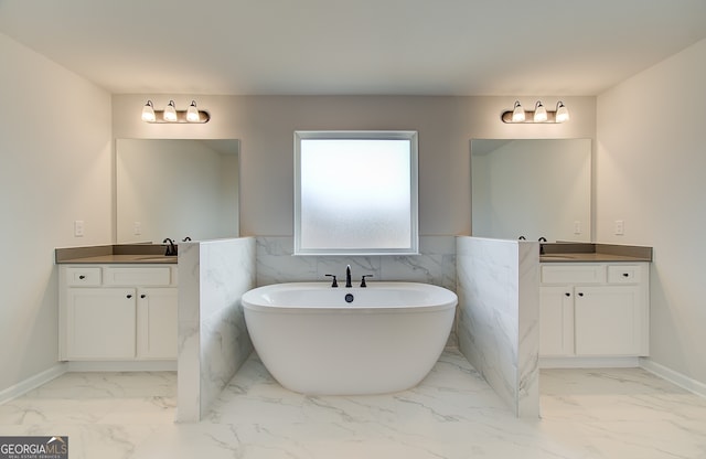 bathroom with a freestanding bath, two vanities, marble finish floor, and a sink