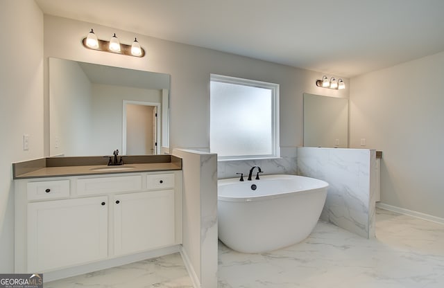 full bath featuring vanity, marble finish floor, and a freestanding bath