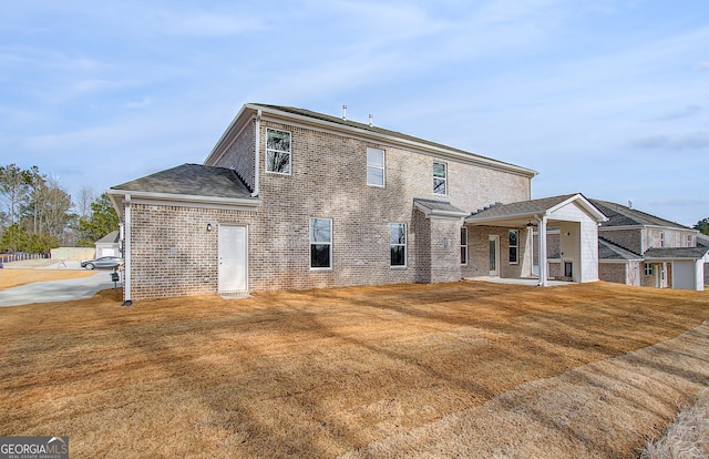 rear view of property with brick siding and a yard