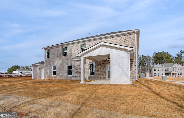 rear view of property featuring a yard, brick siding, a ceiling fan, and a patio area