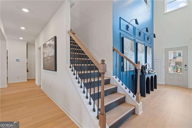 staircase with hardwood / wood-style flooring and a high ceiling