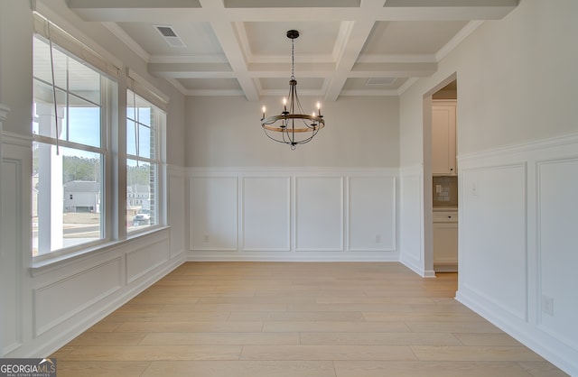 unfurnished dining area with visible vents, an inviting chandelier, beam ceiling, light wood-style floors, and a decorative wall