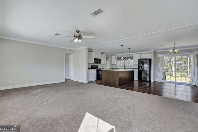 unfurnished living room featuring dark colored carpet, crown molding, ceiling fan with notable chandelier, and a textured ceiling