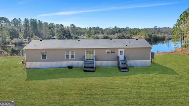 rear view of property featuring a water view and a lawn