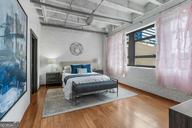 bedroom featuring wood-type flooring, brick wall, and beam ceiling