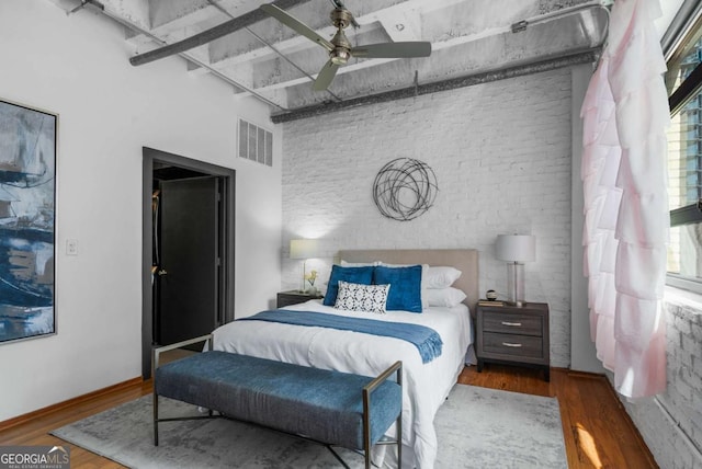 bedroom with a high ceiling, brick wall, hardwood / wood-style floors, and ceiling fan