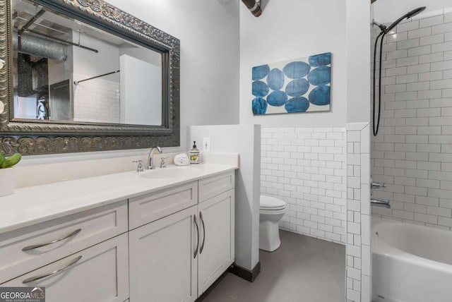 full bathroom with vanity, tiled shower / bath, tile walls, and toilet