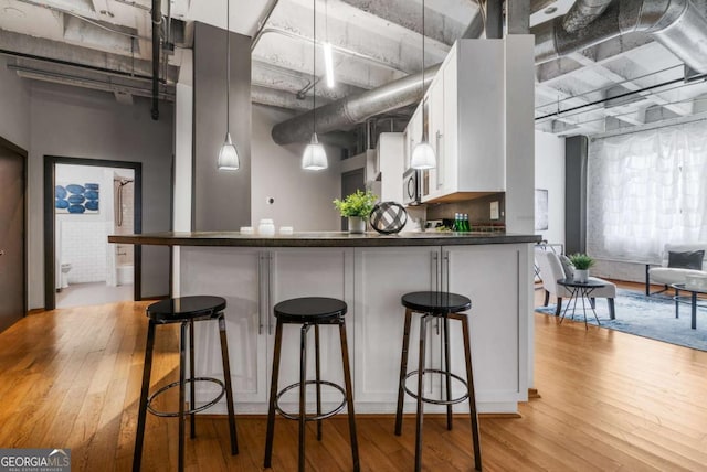 kitchen featuring pendant lighting, a breakfast bar area, white cabinets, and light wood-type flooring