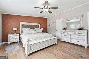 bedroom featuring hardwood / wood-style flooring, ceiling fan, and ornamental molding