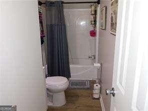 bathroom with shower / tub combo with curtain and toilet