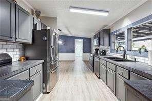 kitchen with stainless steel appliances, tasteful backsplash, sink, and light hardwood / wood-style flooring