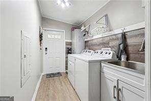 washroom with washing machine and dryer, crown molding, and light wood-type flooring