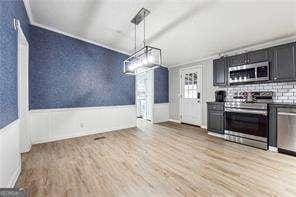 kitchen with stainless steel appliances, light hardwood / wood-style flooring, and decorative light fixtures