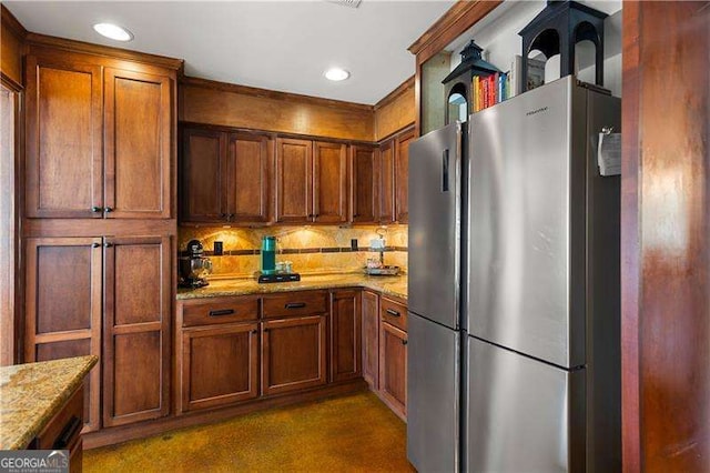 kitchen featuring decorative backsplash, stainless steel fridge, and light stone countertops