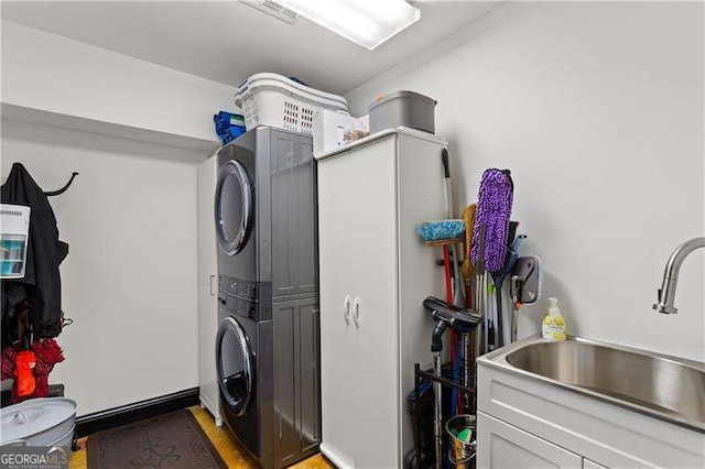 laundry area with sink, cabinets, and stacked washing maching and dryer