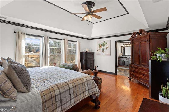 bedroom with ornamental molding, a tray ceiling, ceiling fan, and light hardwood / wood-style flooring