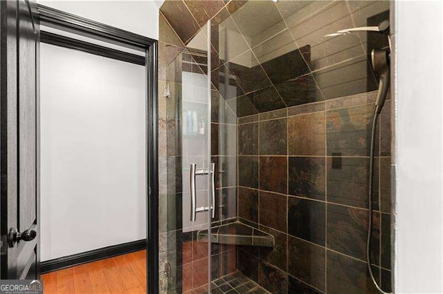 bathroom with an enclosed shower and hardwood / wood-style floors