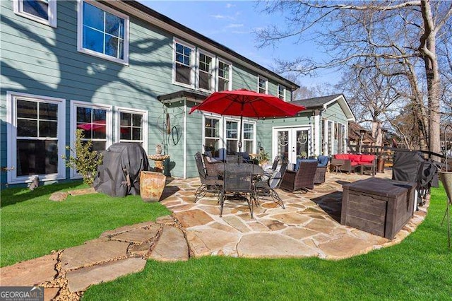 rear view of house with a lawn, french doors, and a patio area