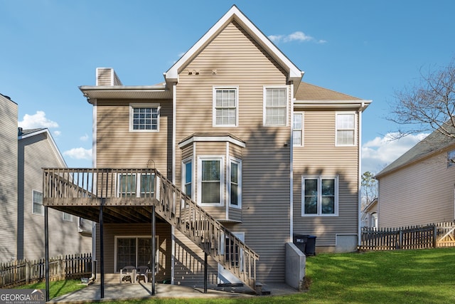 back of property featuring a wooden deck, a yard, and a patio