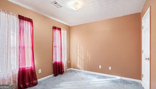 carpeted spare room with a textured ceiling