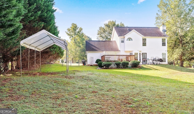 rear view of property featuring a carport, a yard, and a deck