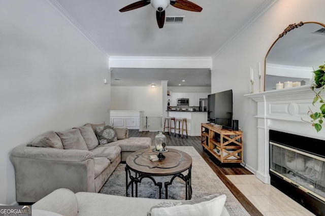 living room with ceiling fan, ornamental molding, and light hardwood / wood-style floors