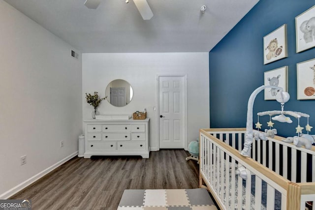 bedroom with a crib, hardwood / wood-style floors, and ceiling fan