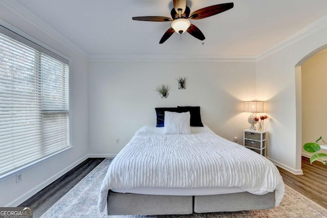 bedroom with ceiling fan, ornamental molding, and wood-type flooring