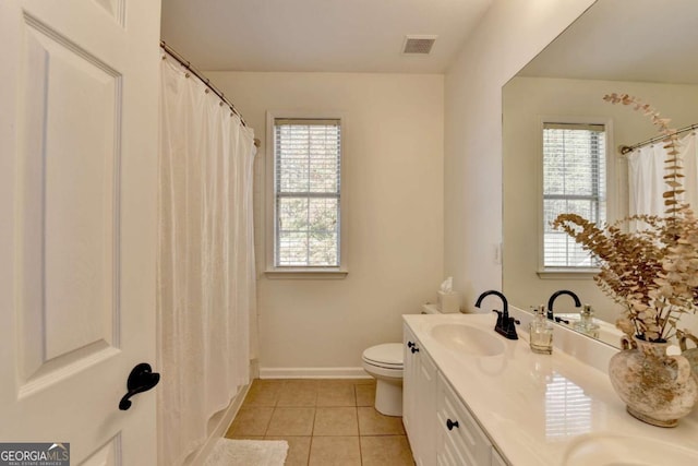 bathroom featuring tile patterned floors, toilet, vanity, and a wealth of natural light