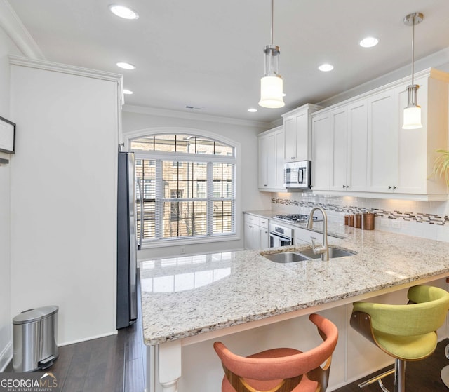 kitchen featuring pendant lighting, sink, a breakfast bar, appliances with stainless steel finishes, and white cabinetry