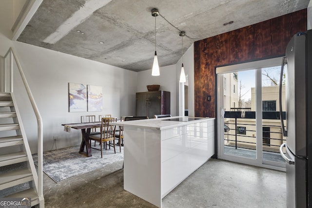 kitchen with white cabinetry, black electric stovetop, stainless steel fridge, and concrete floors