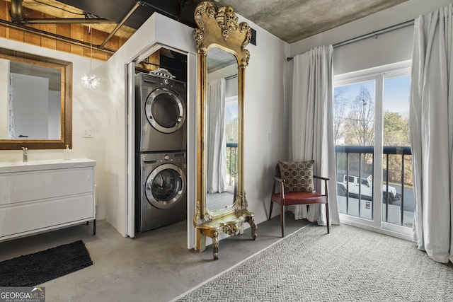 washroom with stacked washer / drying machine and sink