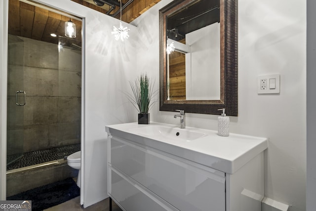 bathroom with vanity, a shower with door, and toilet