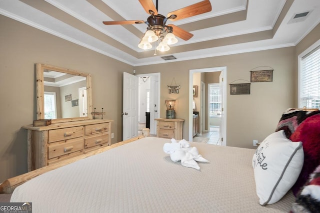 bedroom featuring crown molding, connected bathroom, a tray ceiling, and ceiling fan