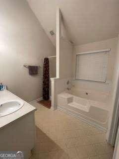 bathroom featuring vanity, tile patterned flooring, vaulted ceiling, and tiled bath