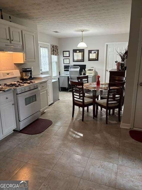 kitchen featuring hanging light fixtures, white cabinetry, white range with gas cooktop, and a textured ceiling