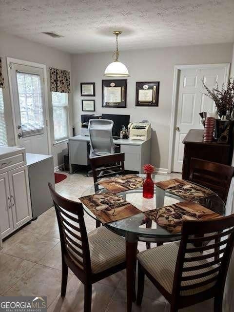 dining space featuring a textured ceiling and light tile patterned flooring