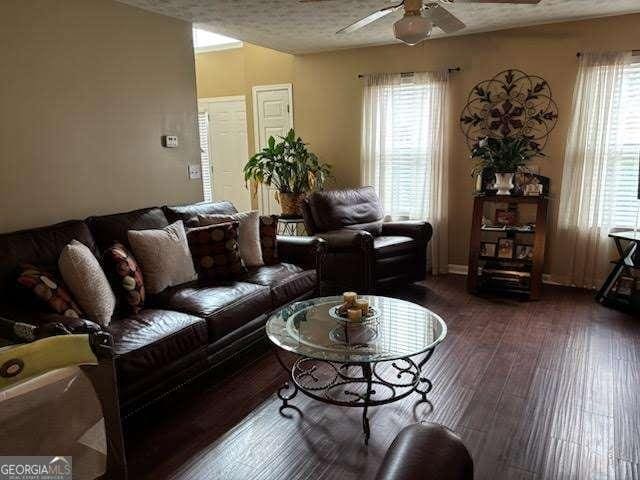 living room with dark hardwood / wood-style flooring, a textured ceiling, and ceiling fan