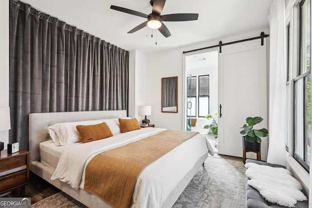 bedroom with multiple windows, a barn door, access to exterior, and ceiling fan