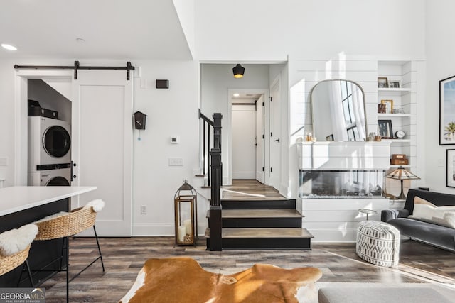 interior space with dark wood-type flooring, a barn door, and stacked washer / dryer