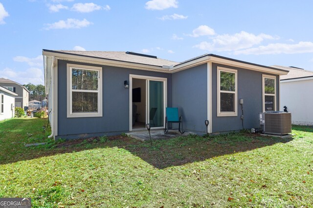 rear view of house featuring a lawn and central air condition unit