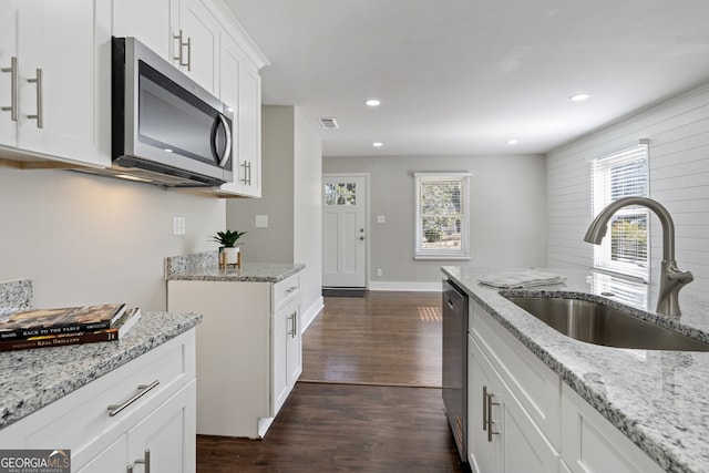 kitchen featuring appliances with stainless steel finishes, white cabinetry, sink, light stone countertops, and a healthy amount of sunlight