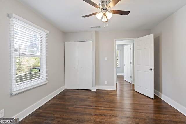 unfurnished bedroom featuring dark wood-type flooring, ceiling fan, and a closet