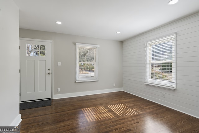 entrance foyer with dark hardwood / wood-style flooring and wooden walls