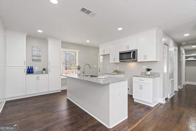 kitchen with a kitchen island with sink, sink, and white cabinets