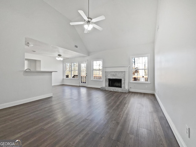 unfurnished living room featuring dark hardwood / wood-style floors, a fireplace, high vaulted ceiling, and a wealth of natural light